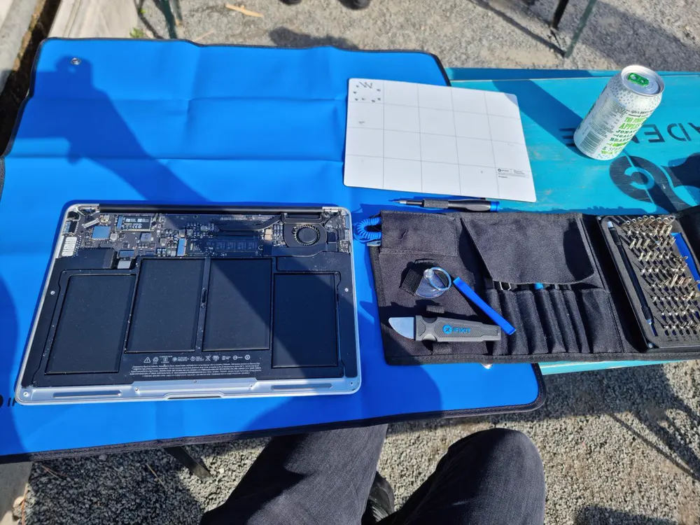 A laptop opened up for repair on a work mat during a visit